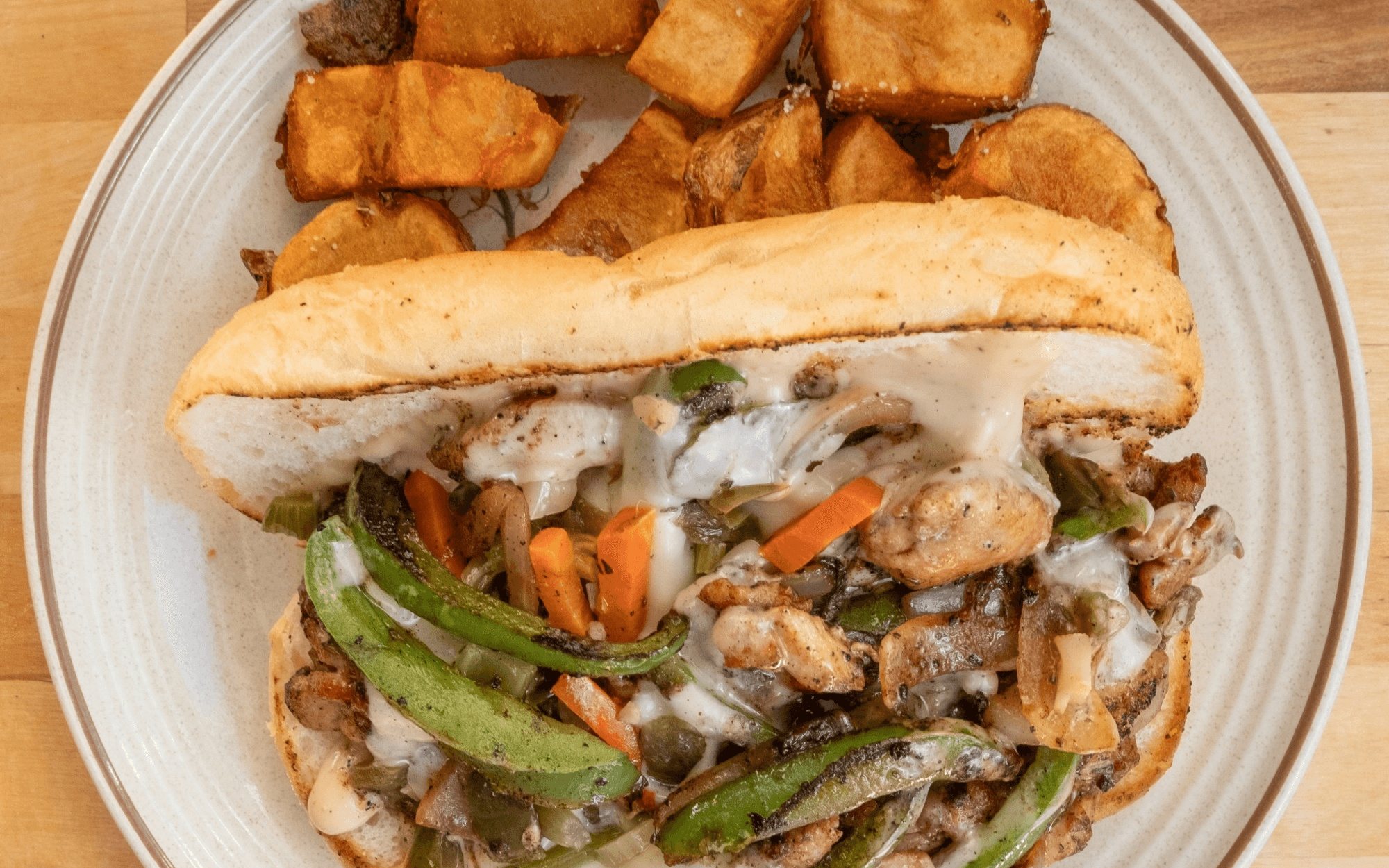 A chicken Philly sandwich with peppers, onions and melted cheese, fried potatoes alongside, at B'Gabs Comfort Cafe