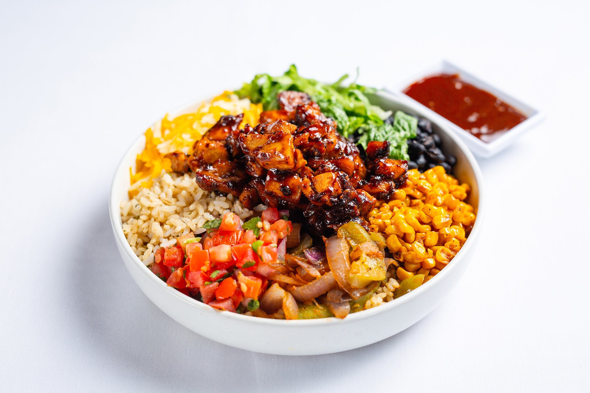 A Litehouse bowl of glazed grilled chicken over brown rice with roasted corn, pico de gallo, peppers and onions