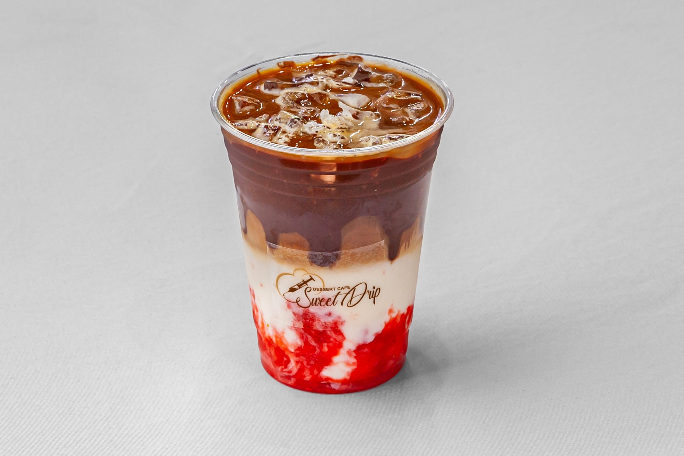 An iced latte in a Sweet Drip cup, espresso over milk and ice