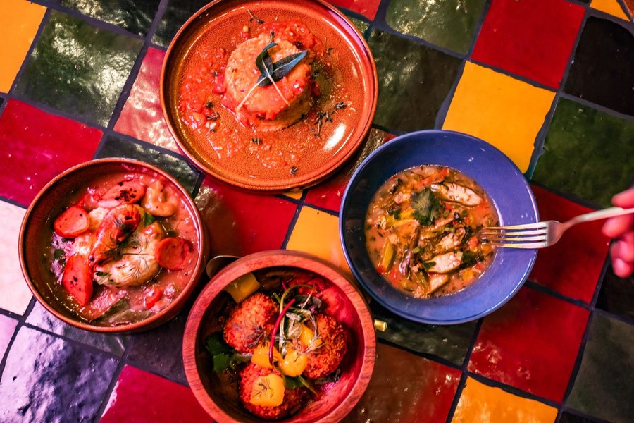 Four Mahari entrées in clay and enamel bowls on a red, yellow and green tiled table