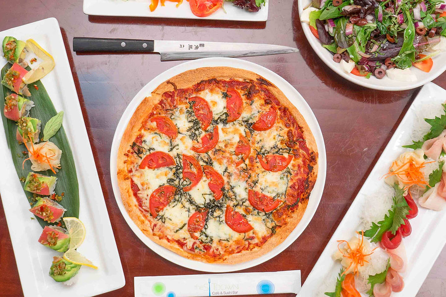 Sushi roll, pizza and sashimi on one table at The Sit Down Café & Sushi Bar
